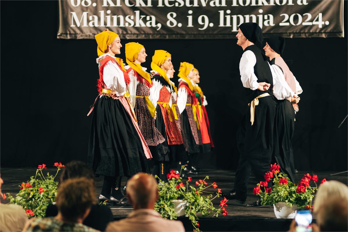 Red plesačica u žutim rupcima nasuprot plesačima u crnim prslucima na Krčkom festivalu folklora u Malinskoj