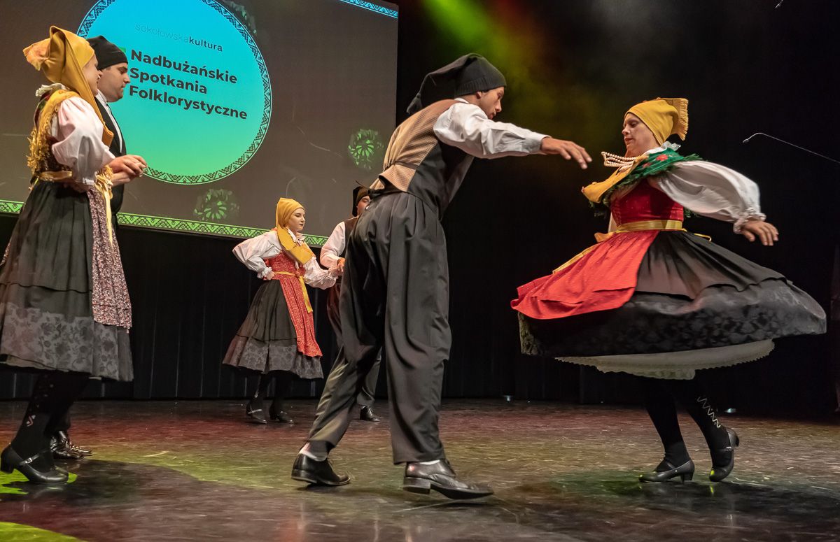 Plesni par KUD-a Punat u vrtnji domaćeg tanca na pozornici festivala u Sokołówu, iza njih natpis festivala