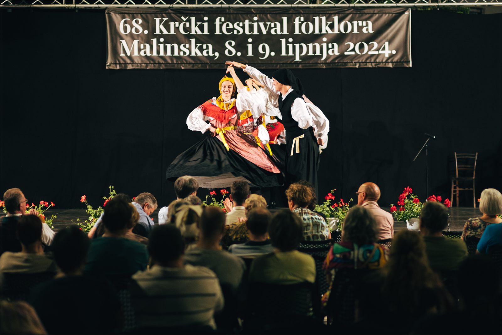 Plesni par u vrtnji na pozornici Krčkog festivala folklora u Malinskoj, ispred publike